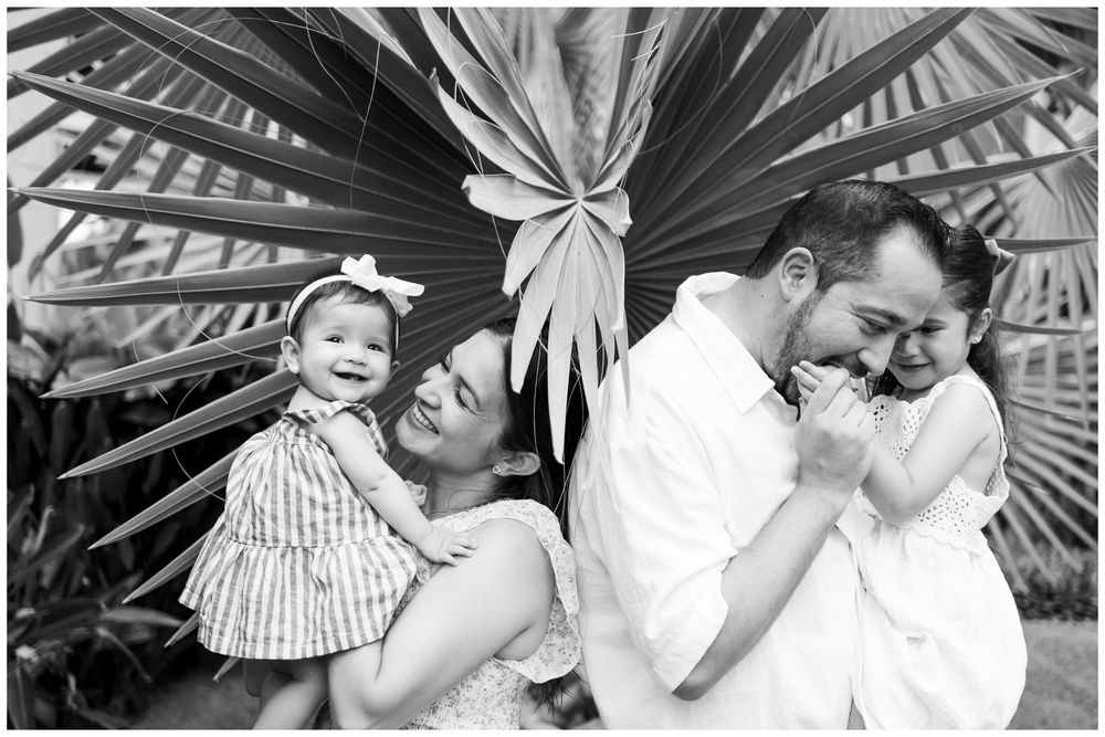 Sayulita family photography, black and white portrait of a happy family with two young daughters laughing together outdoors.