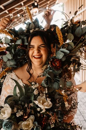 Joyful bride surrounded by lush floral arrangements featuring eucalyptus, roses in a stunning bohemian wedding look near Knoxville, TN.