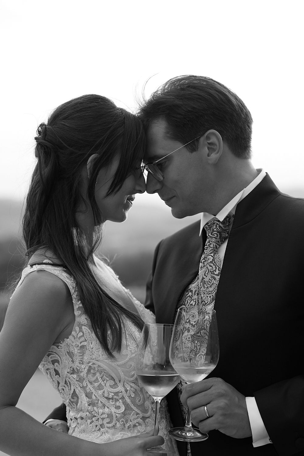 Black and white photo of bride and groom sharing an intimate moment while holding champagne glasses.