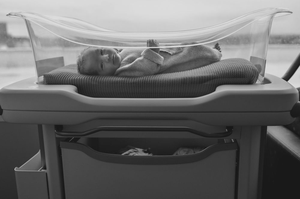 Black and white photo of a newborn baby resting in a hospital bassinet under a clear protective cover.
