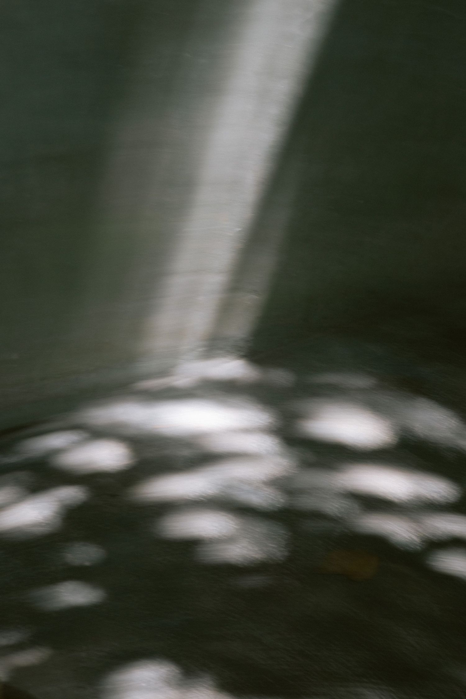 Abstract black and white photo of dappled light and shadows cast on a dark surface.