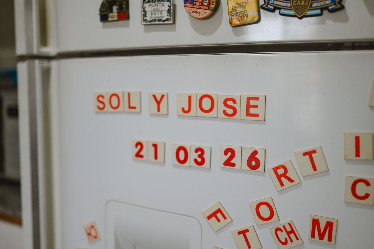 Refrigerator magnets spelling SOL Y JOSE 21 03 26 as a wedding date announcement.