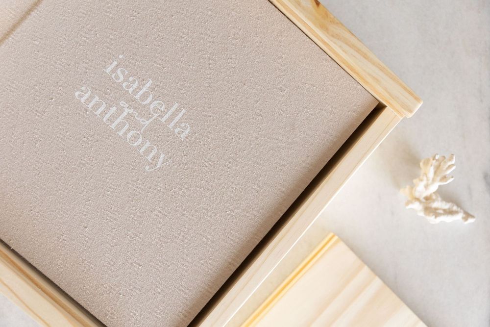 Elegant linen wedding album with embossed names Isabella and Anthony in a wooden keepsake box.