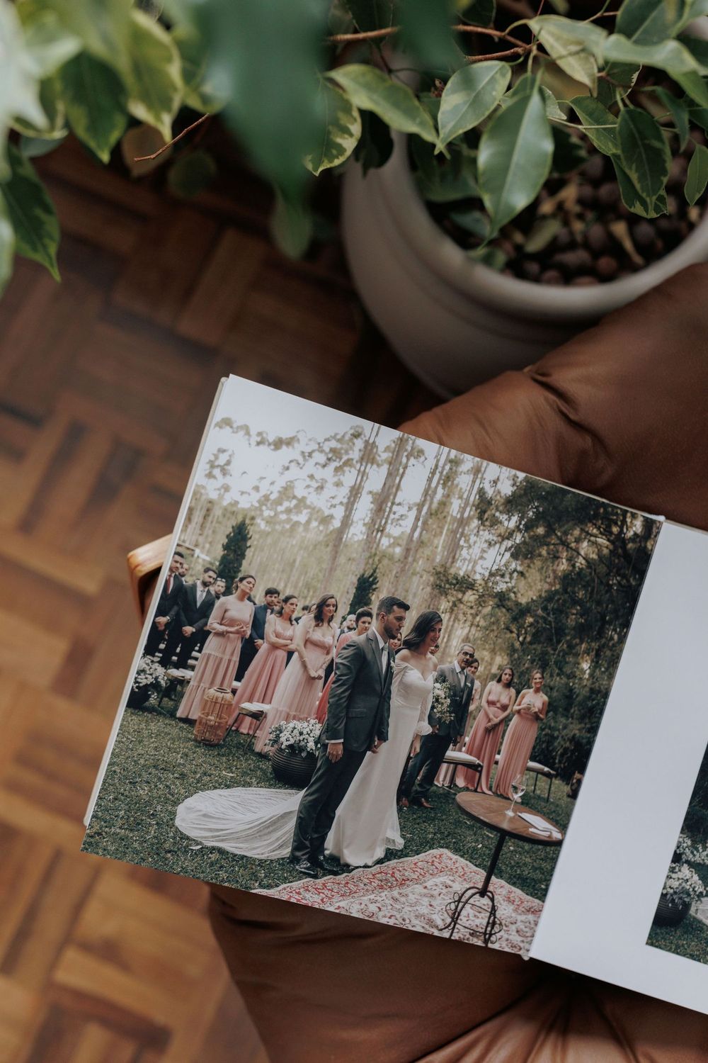 Open wedding photo album showing bride and groom ceremony with bridesmaids in pink dresses outdoors.
