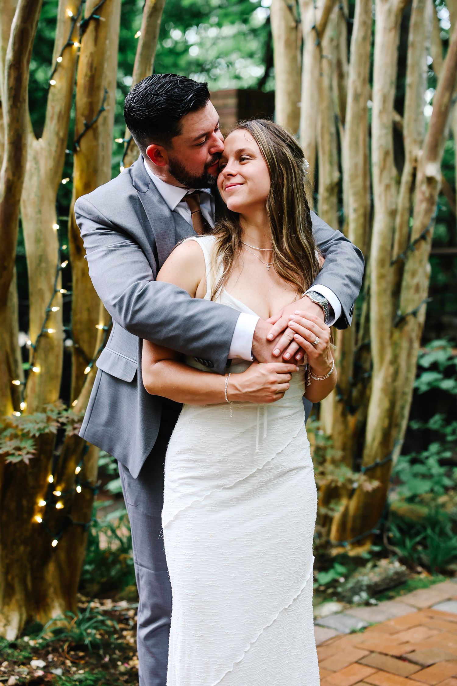 Newlywed couple in wedding attire sharing a tender moment, showcasing their matching wedding bands.