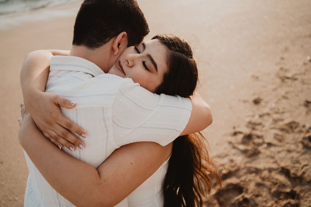 Pareja abrazándose con los ojos cerrados en una fotografía natural de pareja al atardecer.