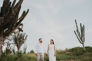 Pareja caminando entre cactus en un paisaje natural de Mazatlán al atardecer.