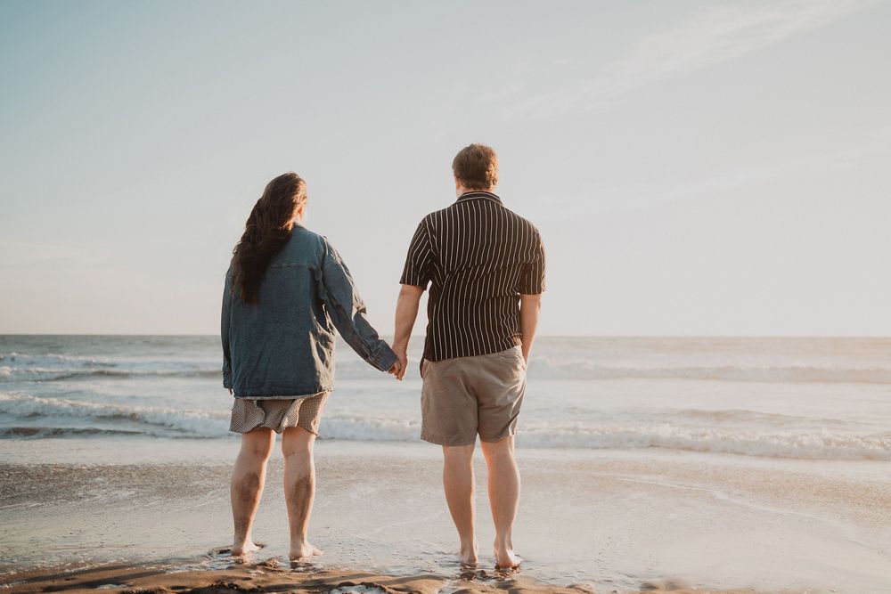 Pareja caminando hacia el mar al atardecer en una sesión de pareja en Mazatlán.
