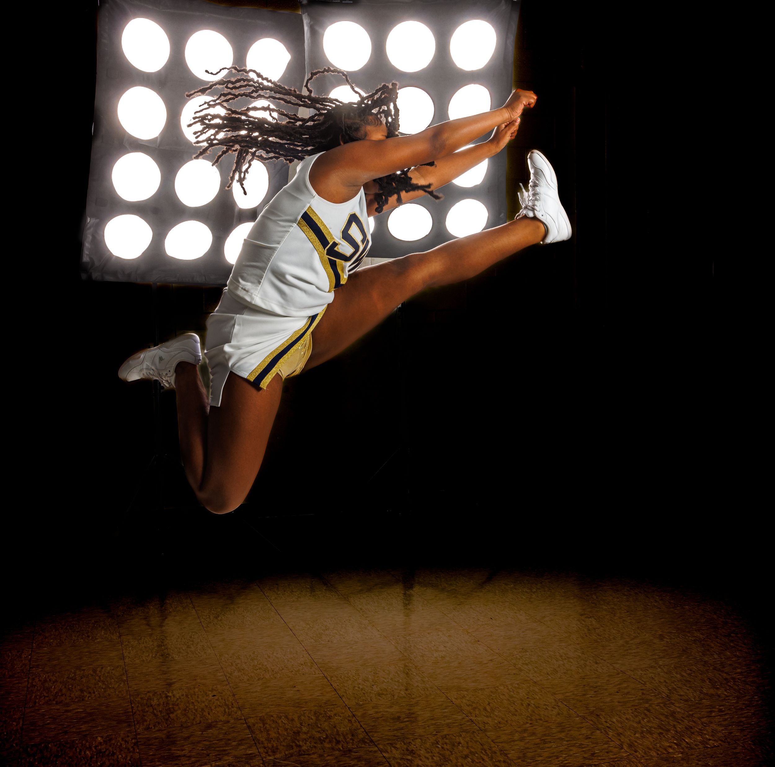 Dramatic photo of an athlete leaping against bright spotlights in a dark setting.