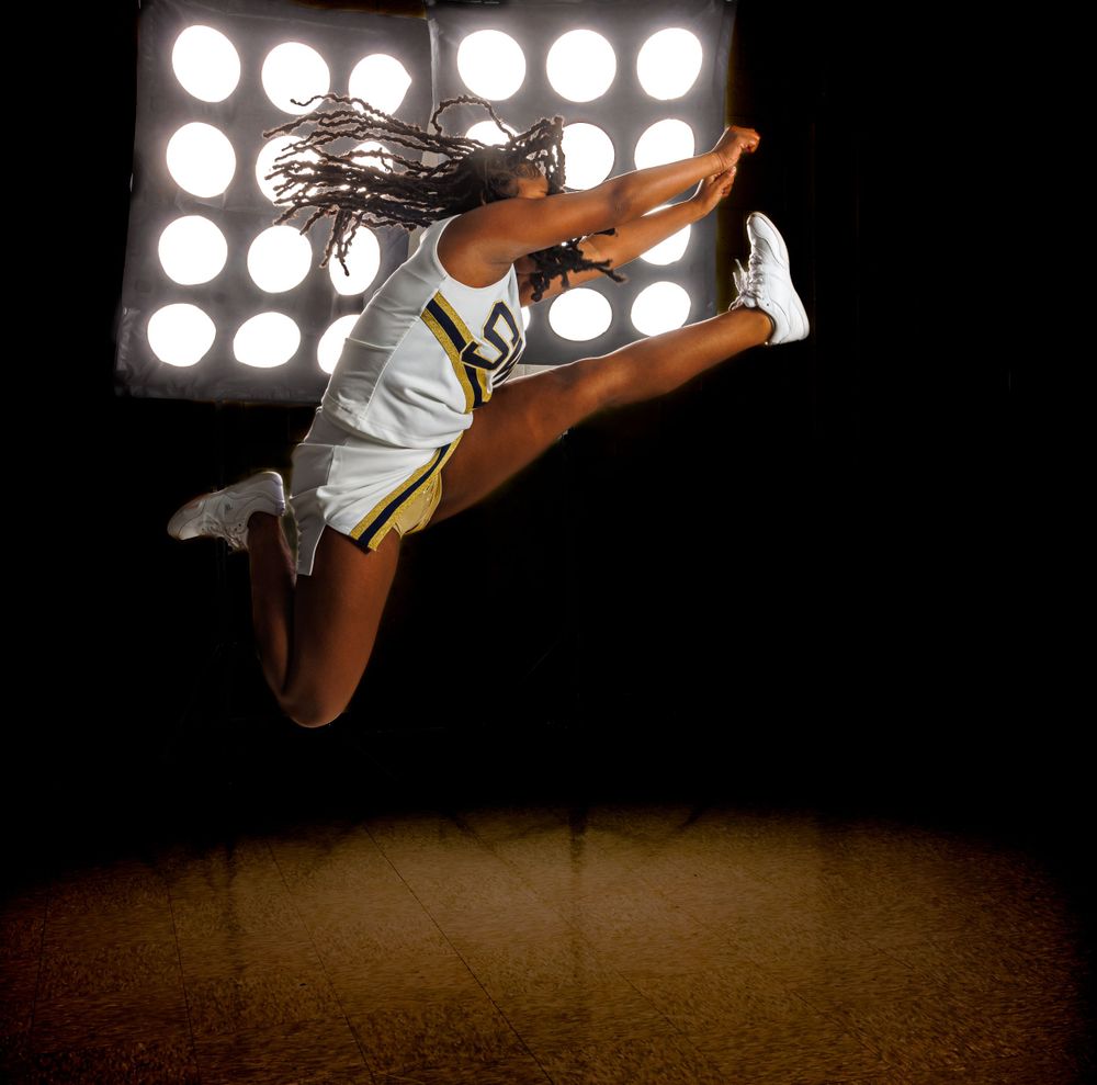 Dramatic photo of an athlete leaping against bright spotlights in a dark setting.
