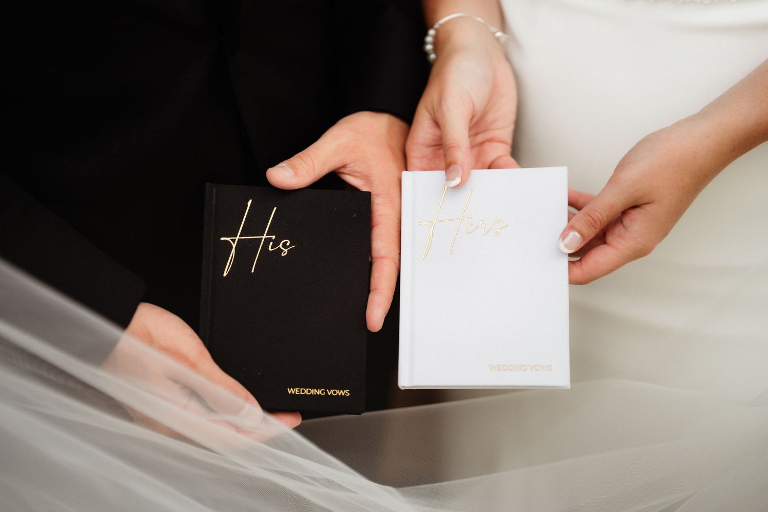 Bride and groom holding matching black and white His and Hers wedding vow books during ceremony.