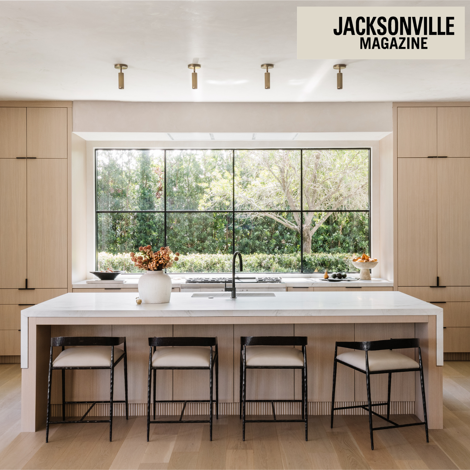 White oak kitchen with large window and greenery outside