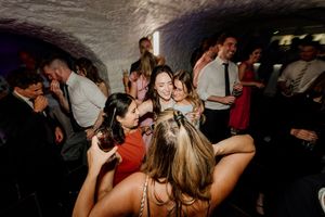 Friends dancing and celebrating at a lively indoor party in a cave-like venue with dim lighting.