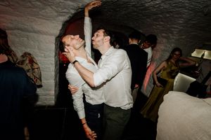 Couple dancing closely together at a wedding reception in a rustic stone-walled venue.