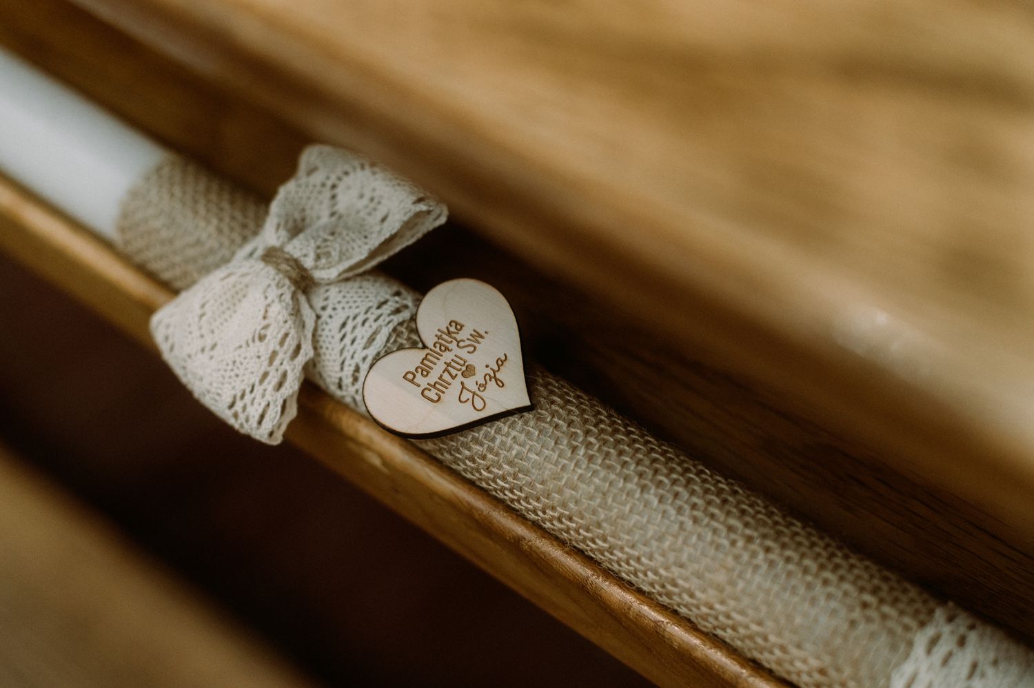 Wooden heart wedding favor with lace bow on rustic church pew bench decoration.