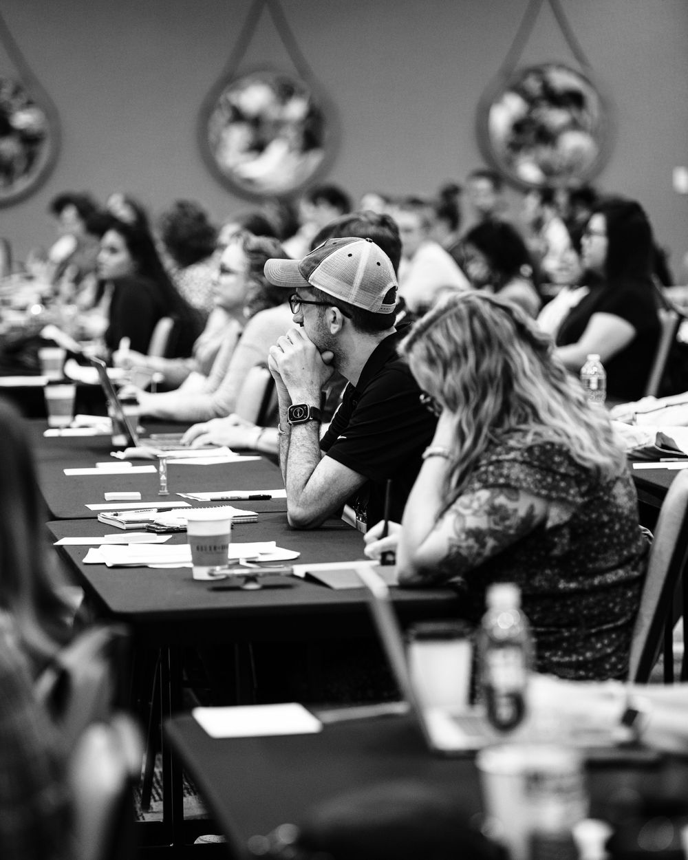 Black and white photo of attendees seated at tables during a conference or seminar event.