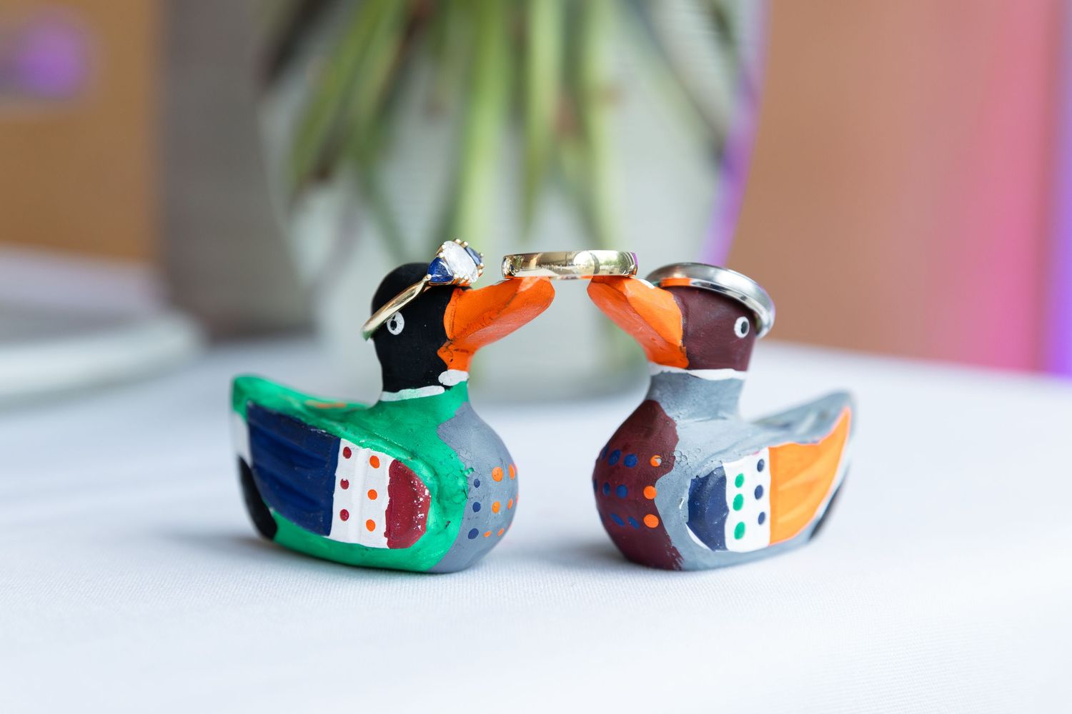 Two colorful hand-painted wooden duck figurines with wedding rings sitting on top of them at the civic garden complex in london, ontario.
