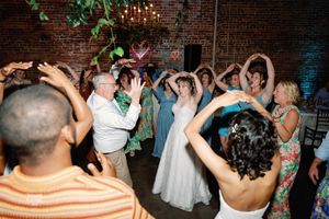 Bride and guests dancing with arms raised at a wedding reception inLGBTQ+ Wedding Photographer, Booth Creative Co. Wilmington, NC Weddings,