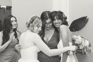 Bride shares an emotional hug with bridesmaids in black and white photo before wedding ceremony. Booth Creative Co. Wilmington, NC Wedding