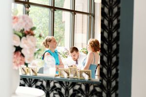 Guests converse at an elegant wedding reception venue with floral arrangements and large windows. Documentary-Inspired wedding photography