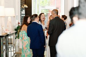 Guests laughing and mingling at an elegant indoor social event with floral decor. Documentary-Inspired wedding photography Wilmington NC