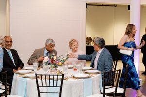 Guests laugh and converse at elegantly set round table during wedding reception. Documentary-Inspired wedding photography Wilmington NC