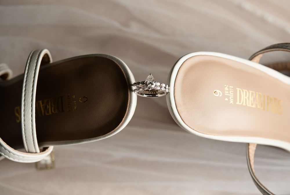 Close-up of two white Dream pairs heeled sandals with silver buckle details on a white background.