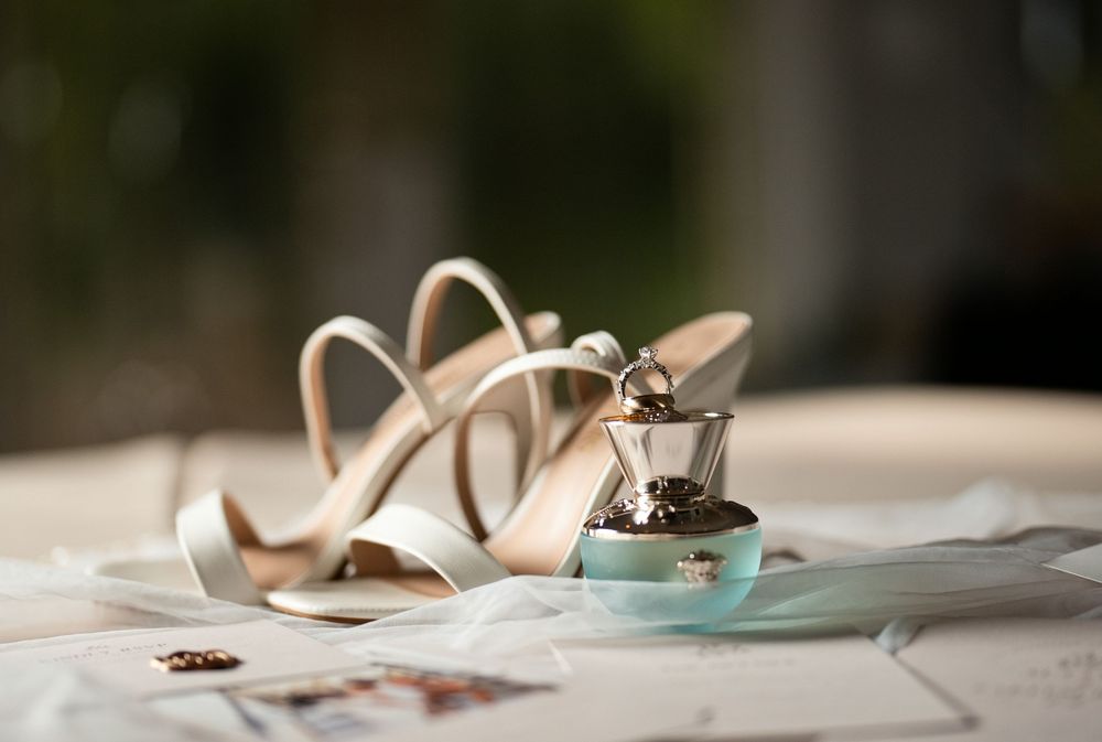 Elegant bridal heels with wedding rings in a tiffany blue box on a white table.