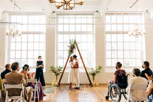 Bright white wedding reception venue with large windows and elegant chandeliers.