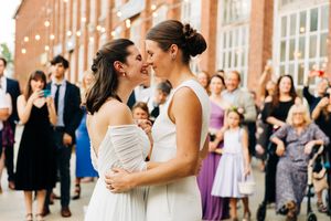 Wedding celebration with guests dancing in front of historic brick building.