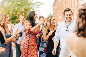 A joyful group celebrates outdoors wearing colorful dresses and formal attire at a summer event.