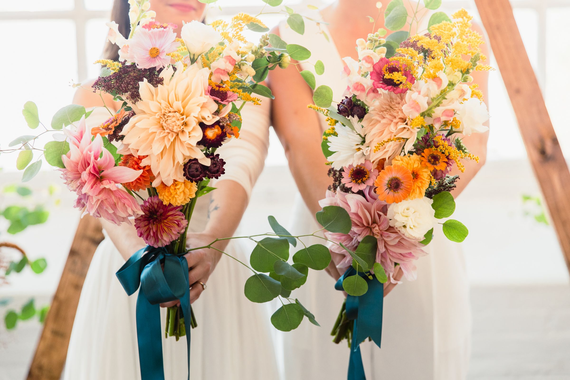 Row of vibrant fall-colored wedding bouquets with orange, pink and burgundy flowers.