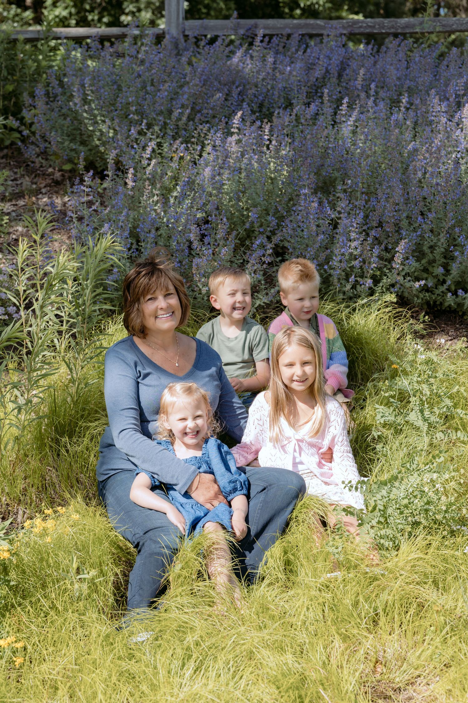 portrait of grandma and all her grandchildren sitting in the flowers during extended family portrait session at powers lake park woodbury MN