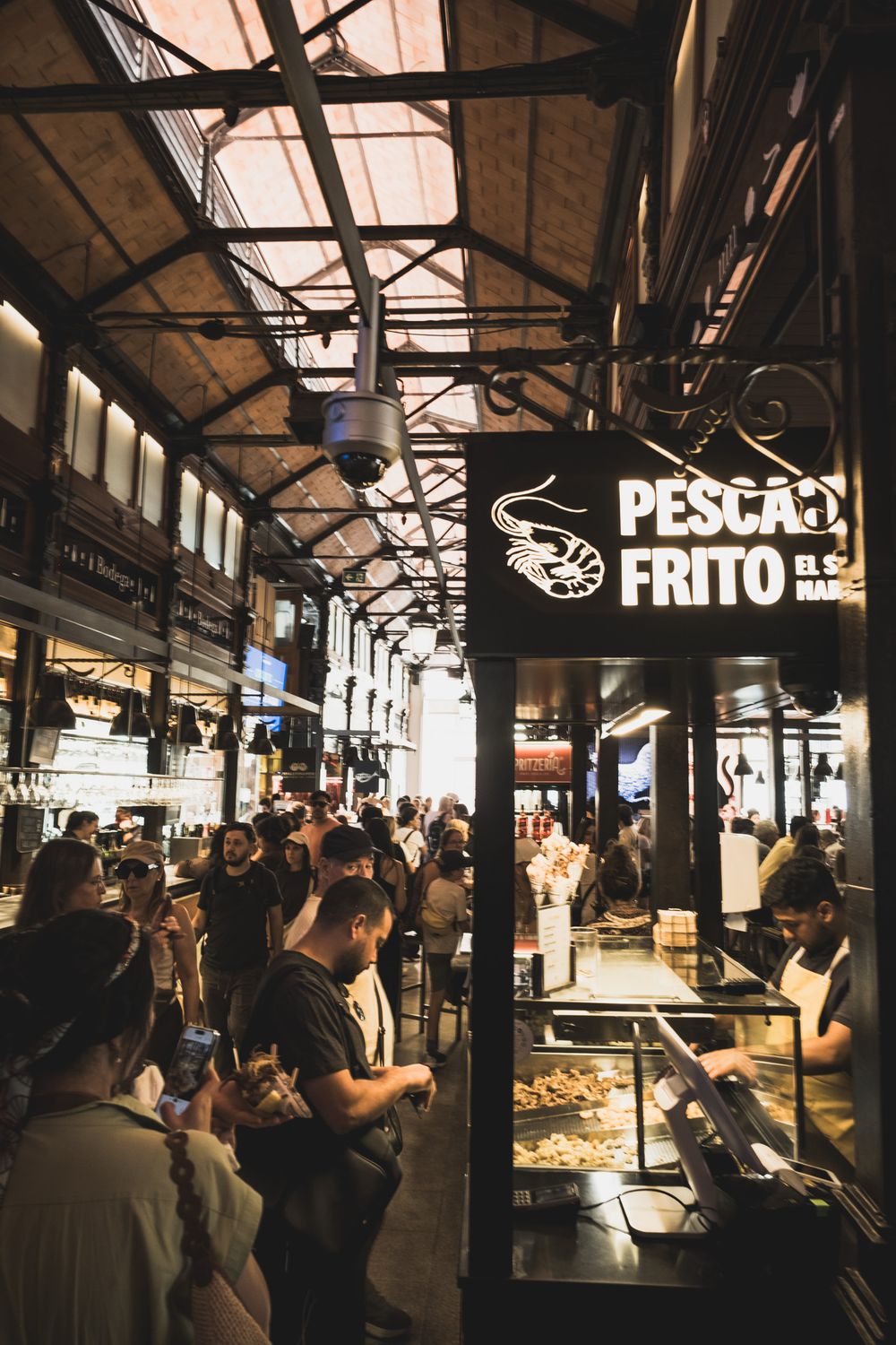 Busy seafood stall Pescado Frito in a historic indoor market with crowds browsing fried fish dishes.