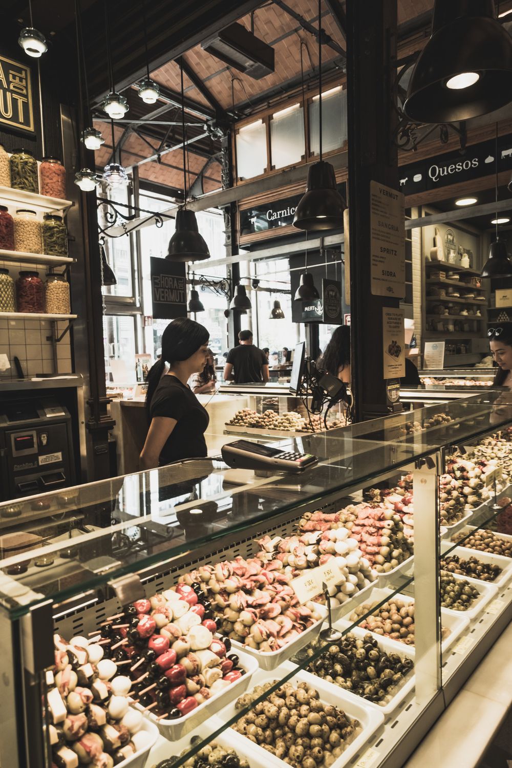 Glass display counter filled with chocolate-covered fruits and sweets at a gourmet indoor food market.