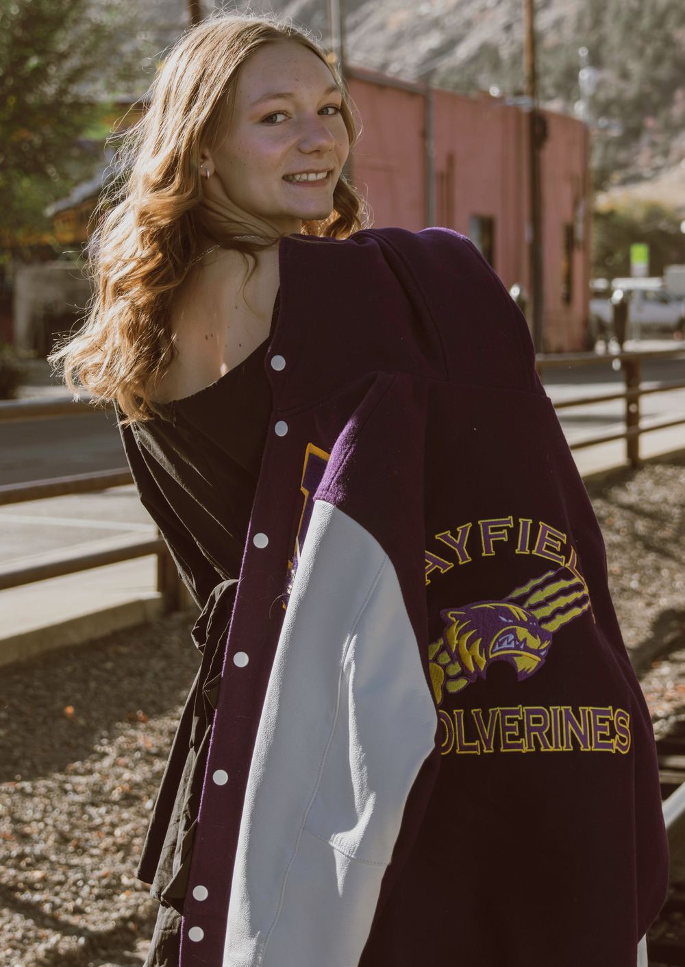 Wearing a Bayfield Wolverines letterman jacket while posing outdoors.