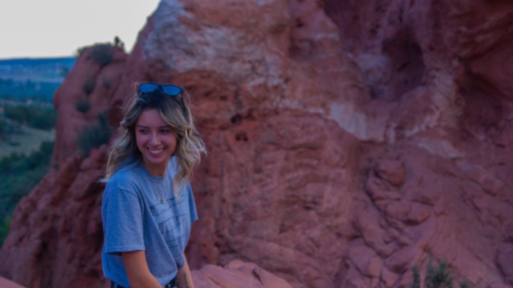 Person enjoying the scenery against red rock formations during sunset.