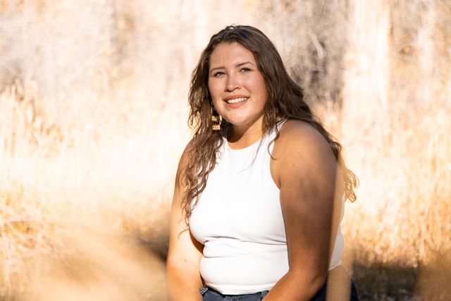 Natural outdoor portrait with warm lighting and textured wall background.
