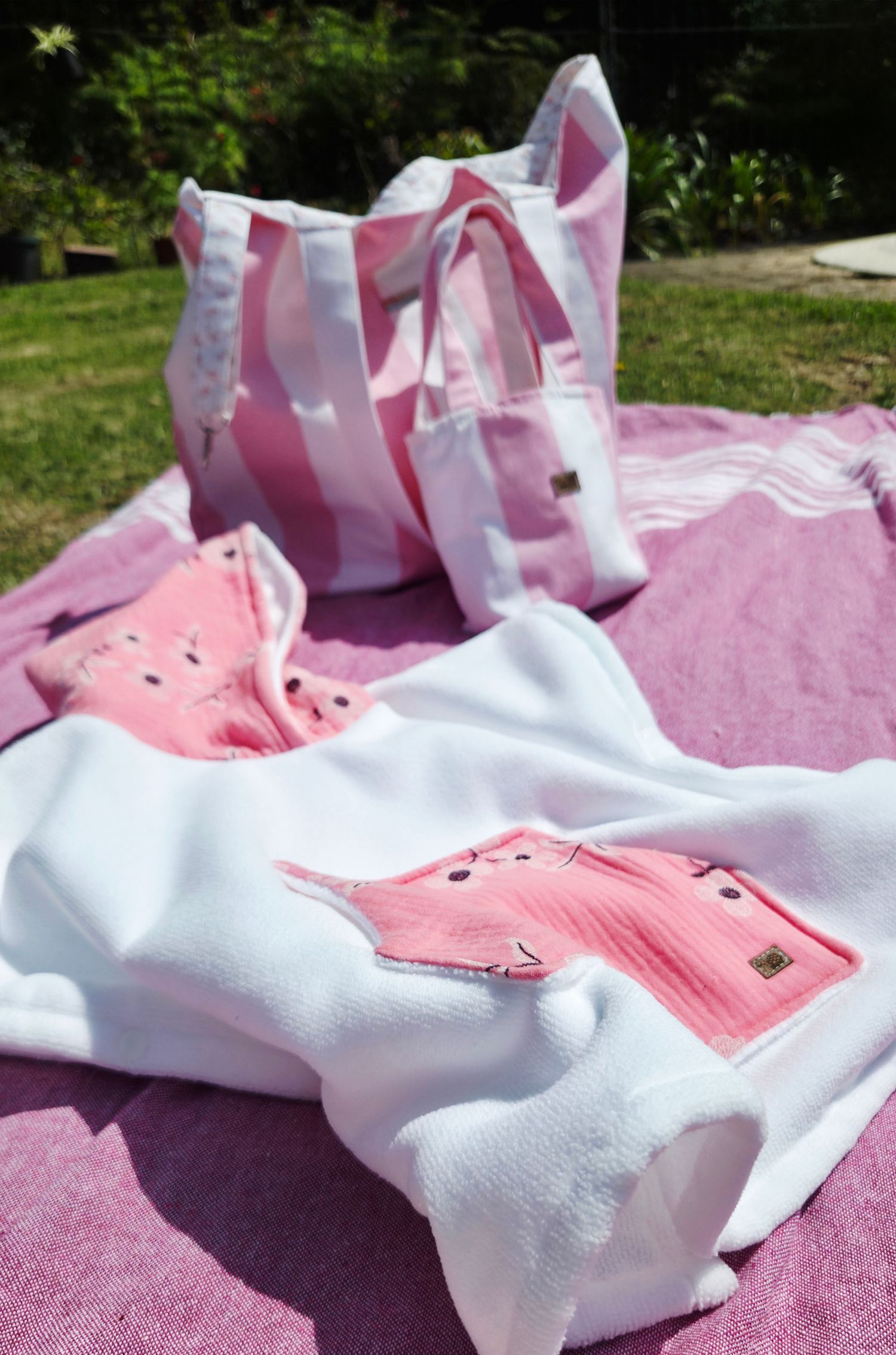 Pink and white striped tote bag with matching white top featuring pink pockets on a pink blanket outdoors.
