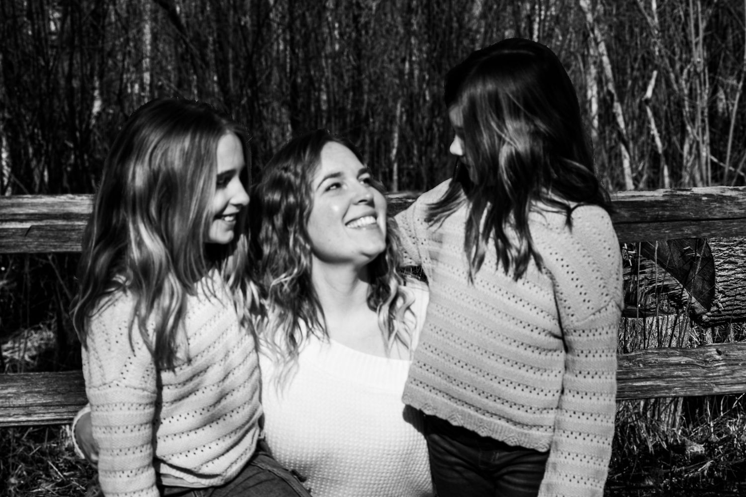 A mother shares a candid moment with her two daughters during a family photography session.