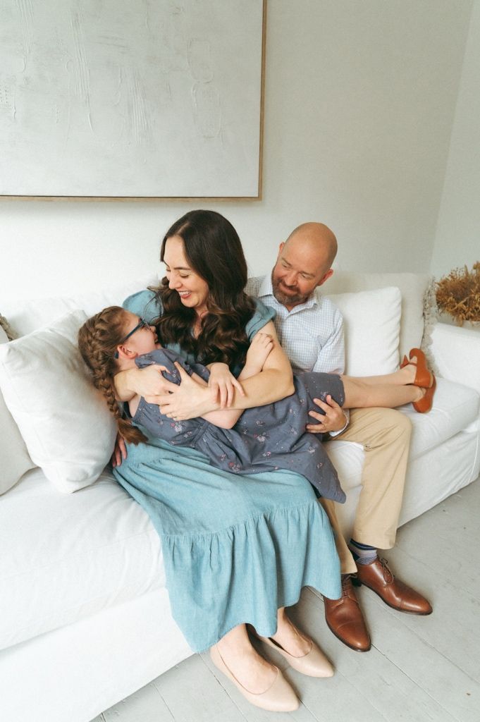 A happy family of three sits on a white sofa at Beverly Harris House in downtown McKinney