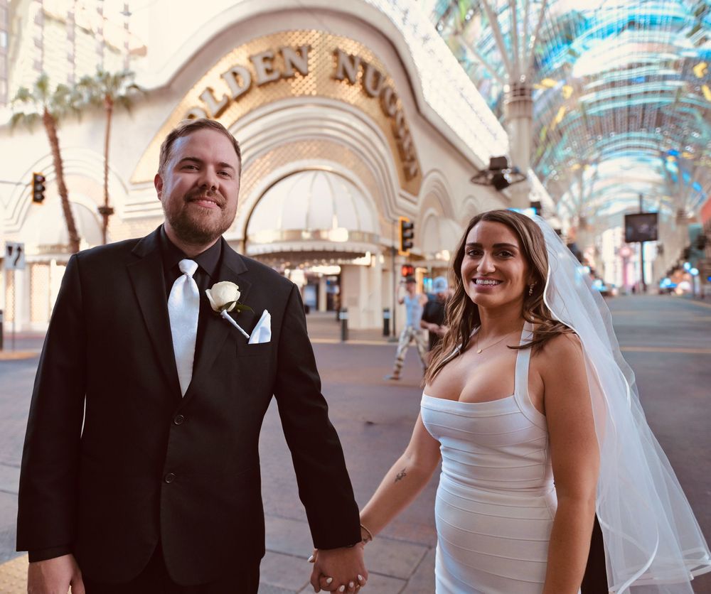 Newlywed couple holding hands in wedding attire outside Golden Nugget casino in Las Vegas.