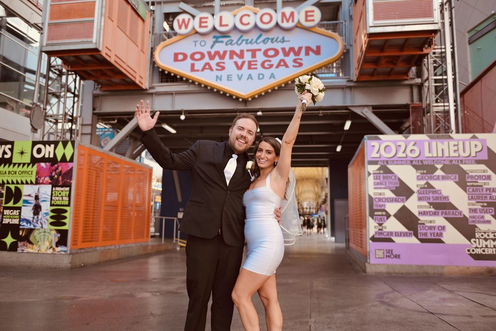 Newlywed couple celebrating in front of the Welcome to Fabulous Downtown Las Vegas sign.