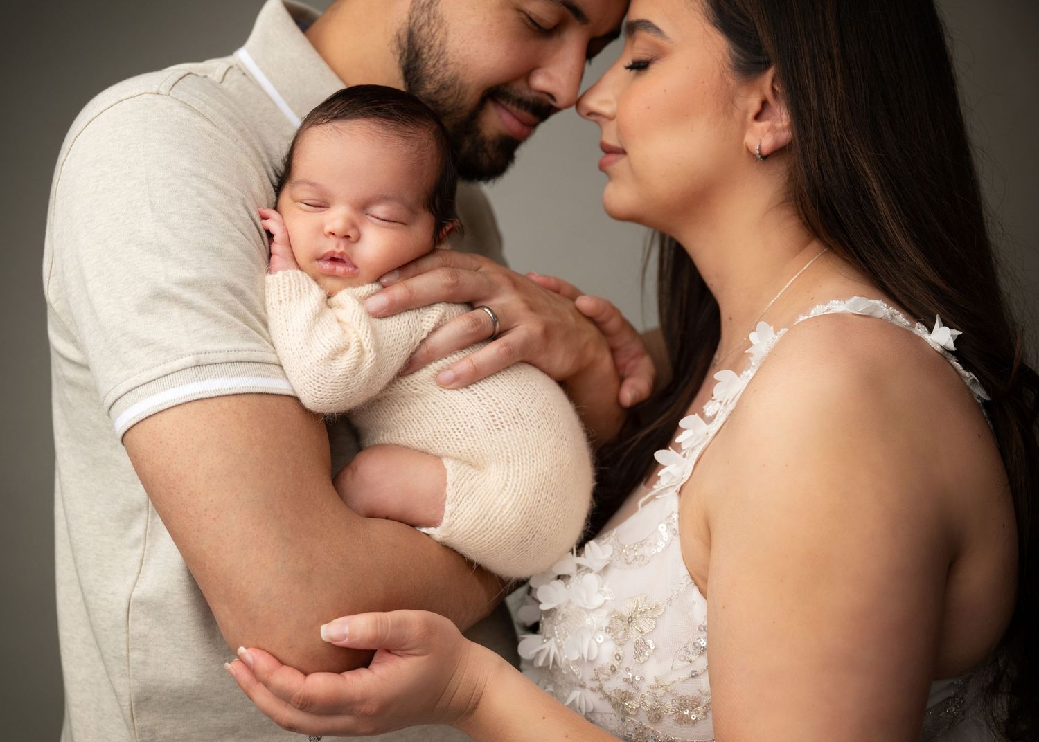 Parents cuddling their sleeping newborn baby during a studio newborn photography session in Linden, New Jersey.
