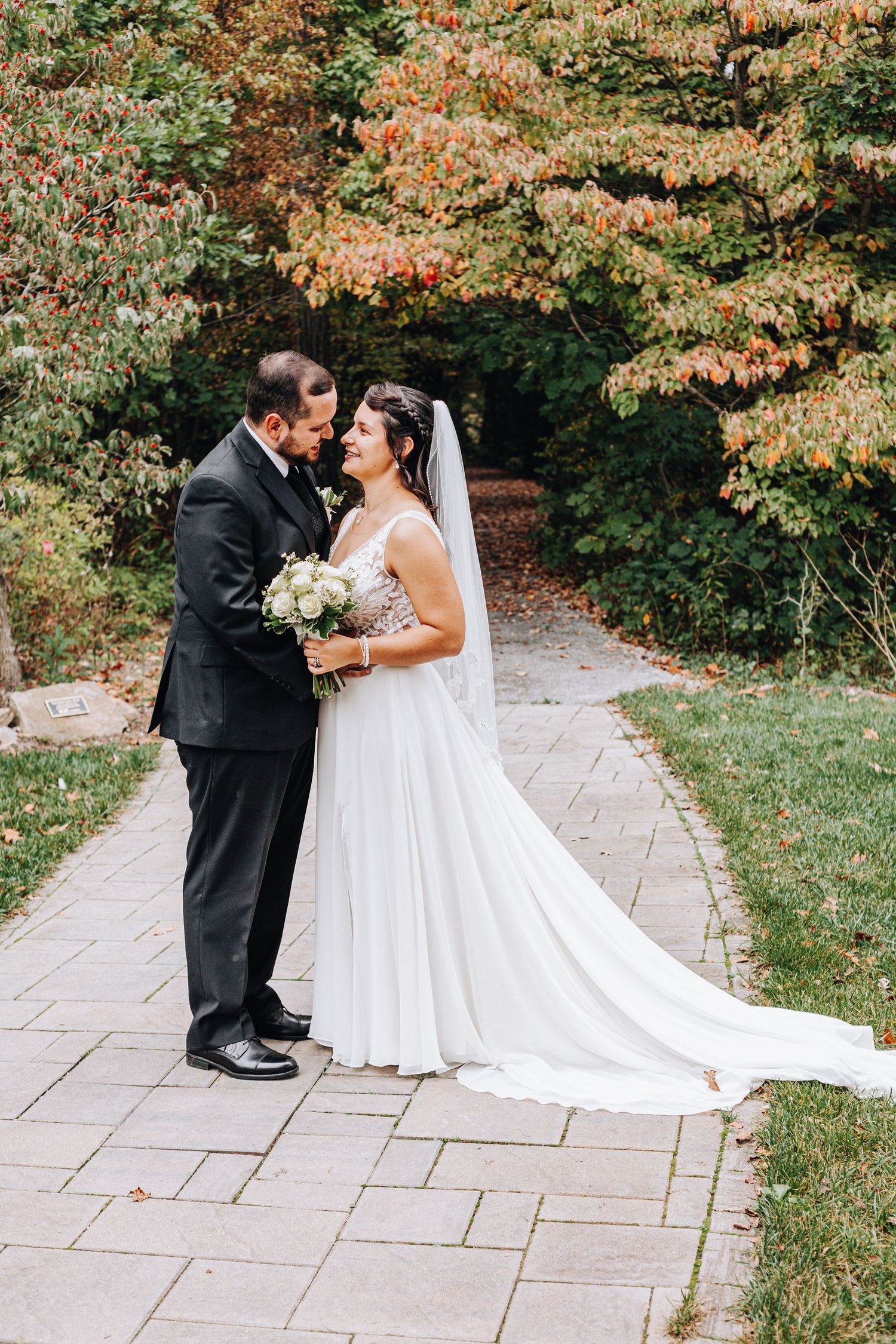 Joyful newlyweds celebrate their outdoor woodland wedding ceremony, raising hands as they walk down the aisle.