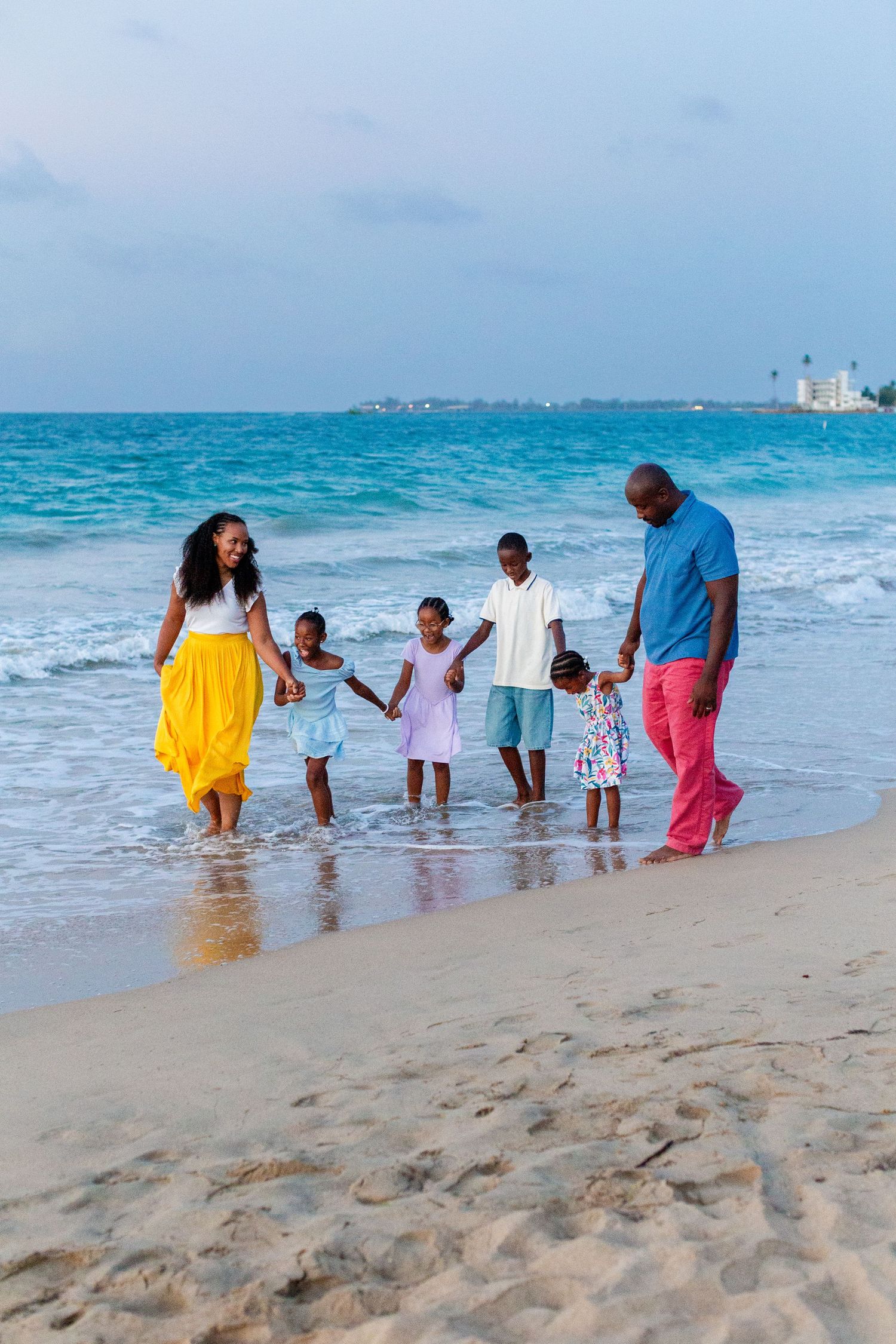 Family portrait. Mom, dad, and four kids holding hands and walking on the beach in Isla Verde, Carolina, Puerto Rico.