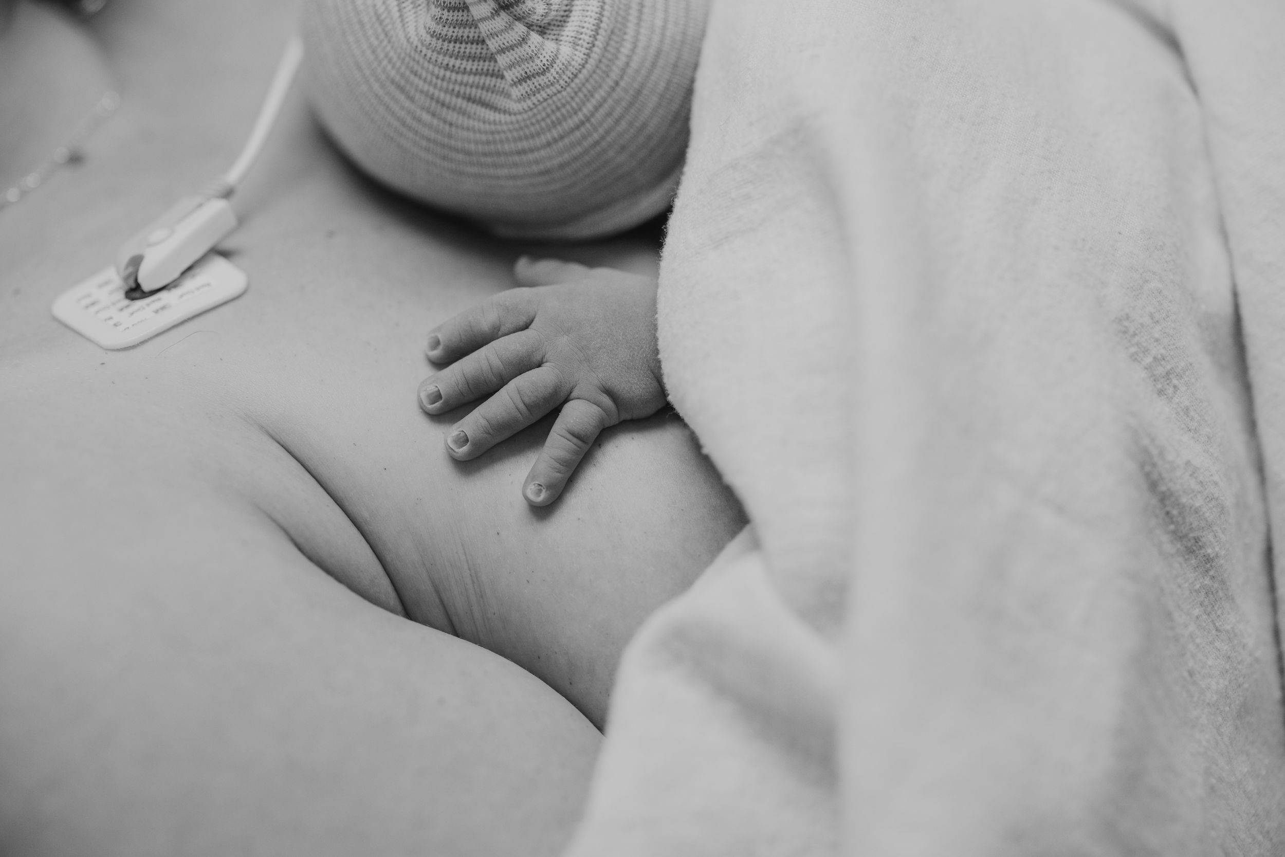Black and white photo of a newborn baby resting on mother's chest during skin-to-skin contact after birth.