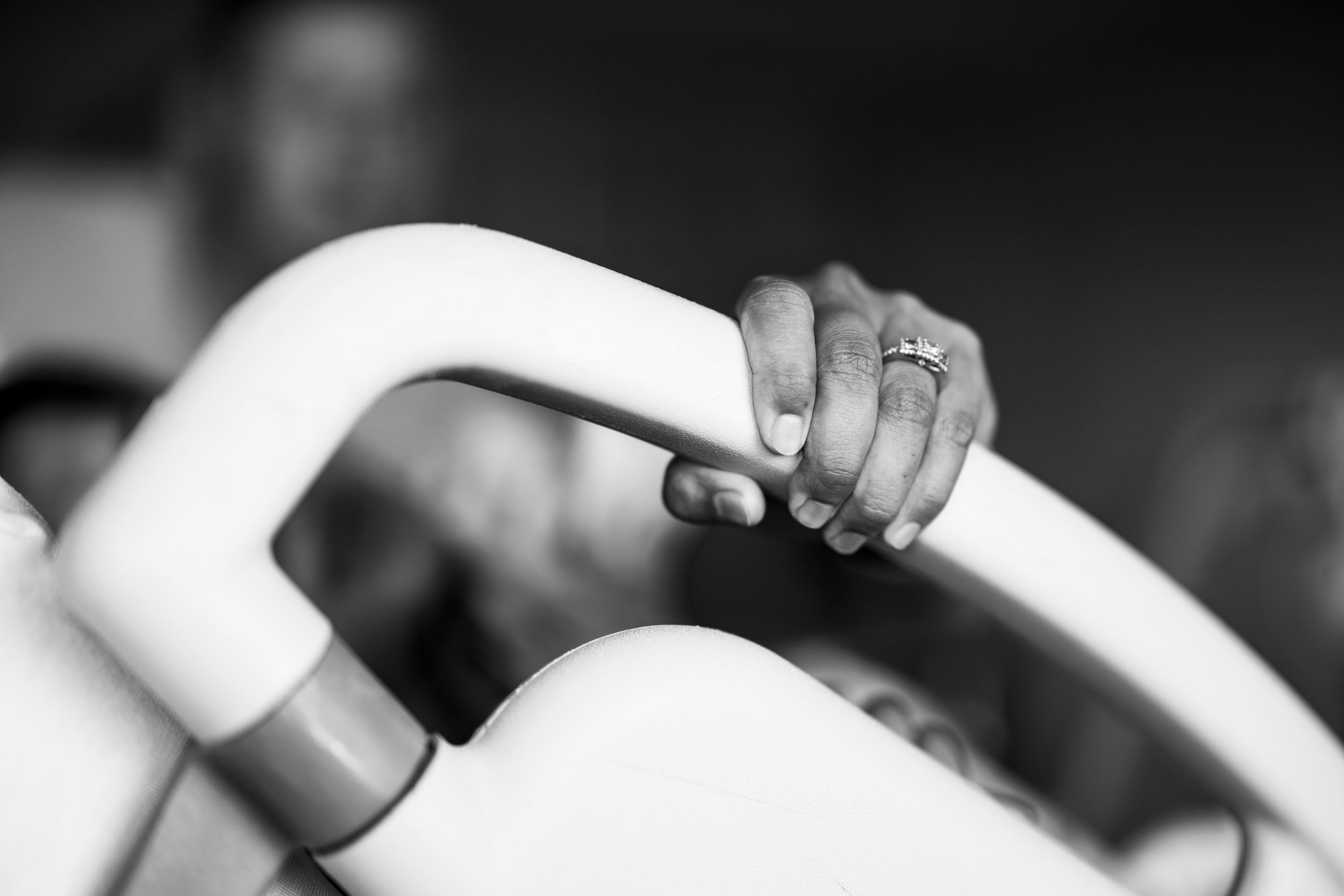 Black and white photo of a hand with a ring gripping a white railing, capturing a moment of tension.