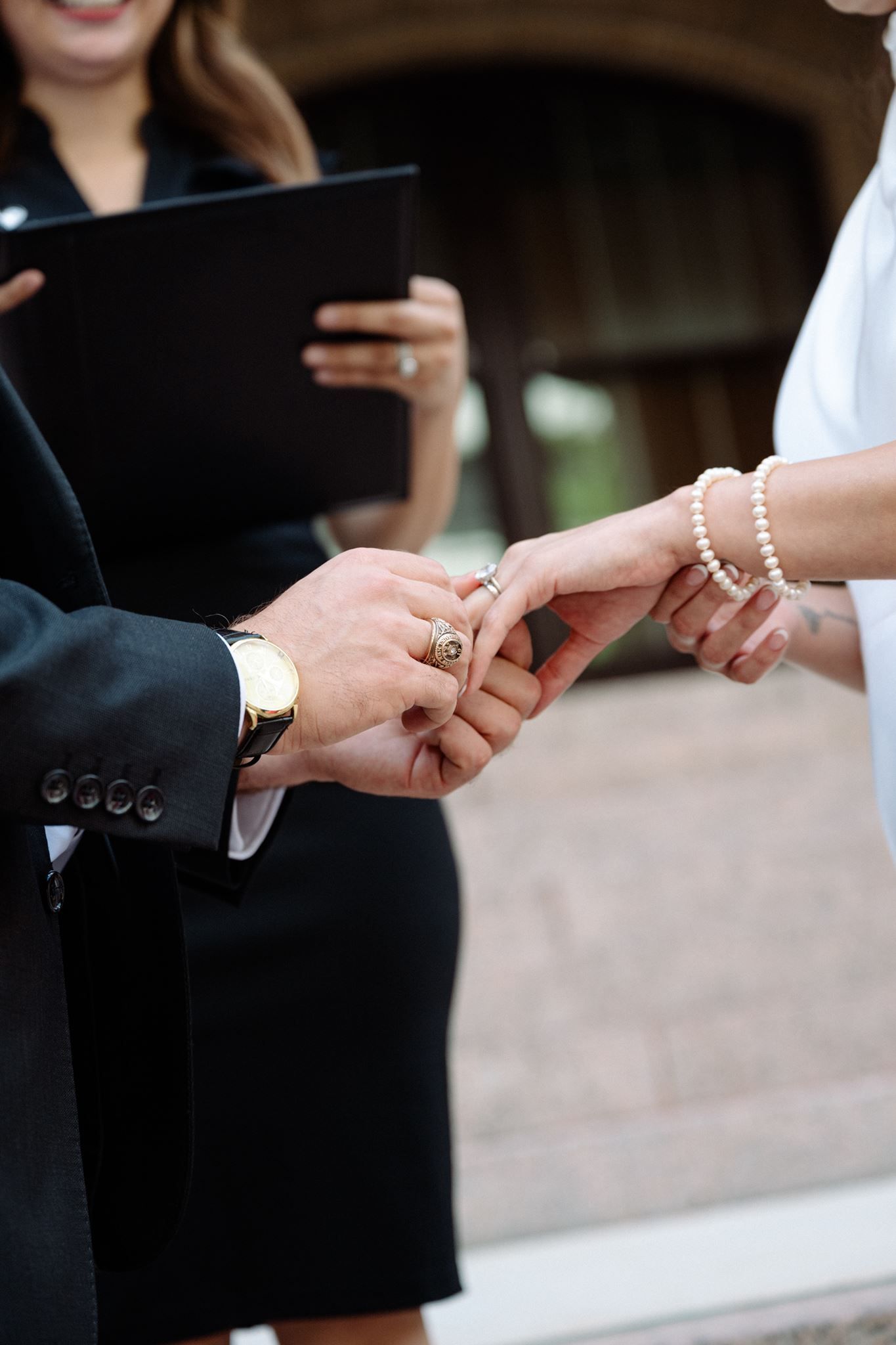 Groom placing ring on bride's hand, standing on steps of the historic 1910 Harris County Courthouse.