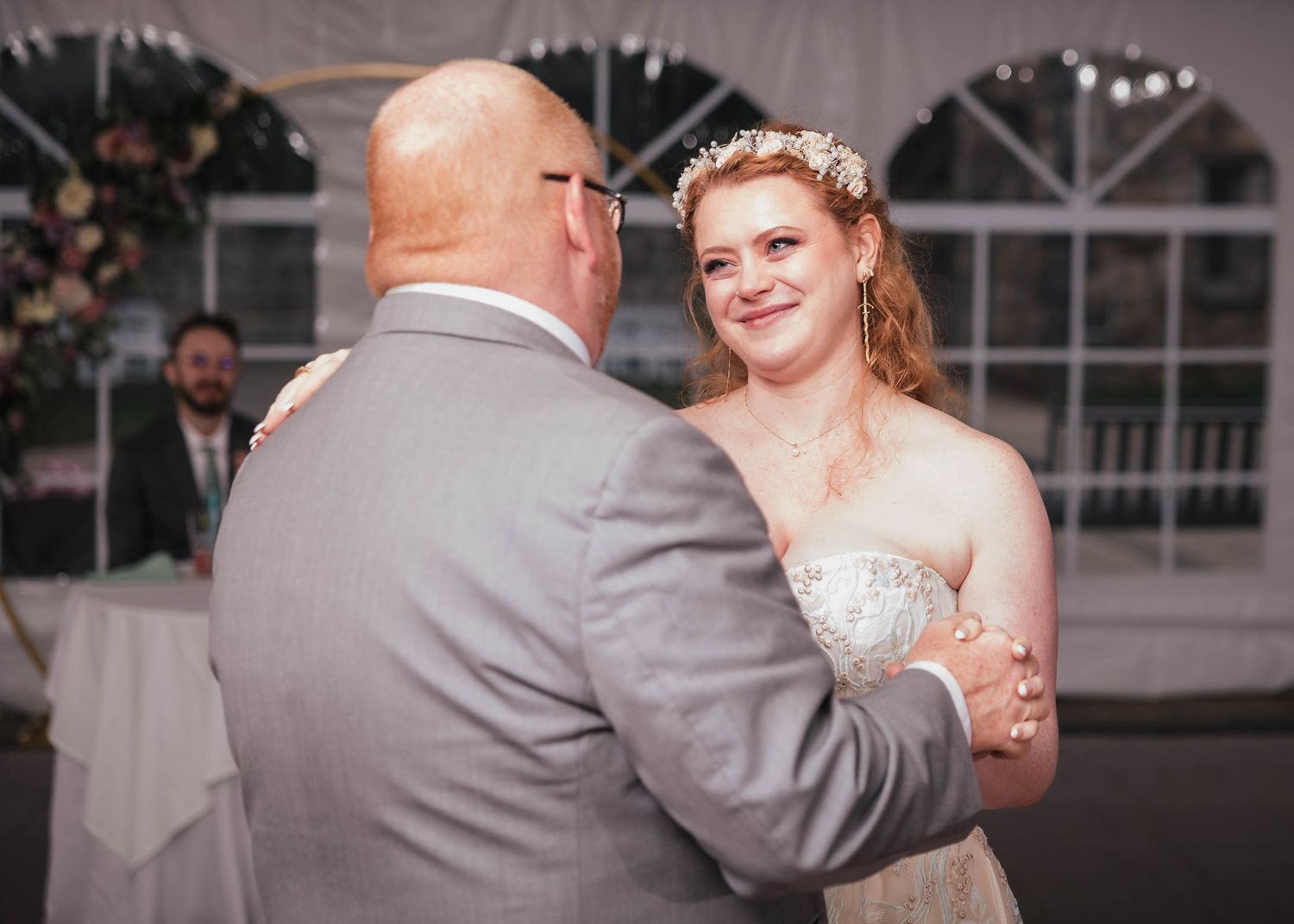 Bride smiling at her father over his shoulder during their dance at the reception.